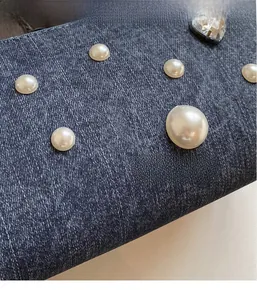 Gros plan sur denim bleu foncé orné de perles blanches et d'un cristal en forme de cœur