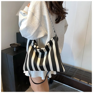 Detail of black and white striped canvas hobo bag with silver chain and leather strap