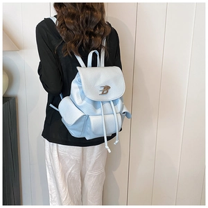 Close-up of light blue leather backpack featuring lychee texture and silver B logo