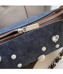 Détail du sac en denim bleu avec décorations de perles et cristaux et zip doré