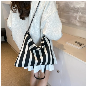 Detail of striped canvas hobo bag with leather chain strap shown in a lifestyle setting