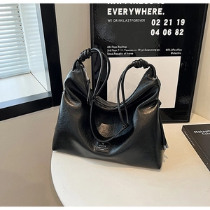 Detail of soft black leather tote with knotted shoulder strap and metal brand plate
