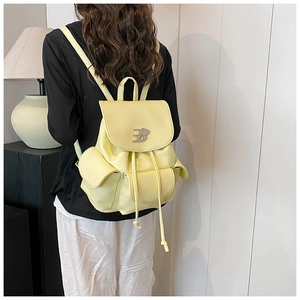 Detail of light yellow leather backpack showing lychee texture and drawstring closure