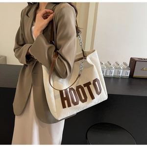 Detail of white tote bag with HOOTO letter patch and leather chain shoulder strap