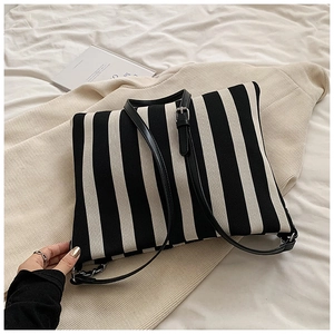 Detail of minimalist black and white striped knit tote with slender leather straps