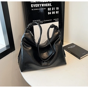 Detail of black hobo bag showing knot strap design and premium soft leather texture