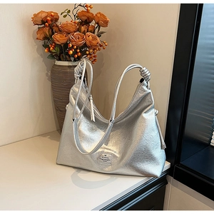 Detailed shot of metallic silver hobo bag with pleated texture and knotted shoulder strap