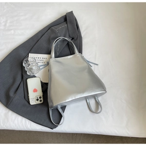 Detailed top view of silver metallic tote bag on blazer with chic urban accessories