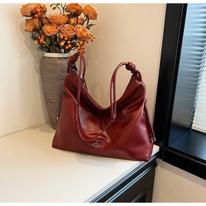 Close-up of deep red tote bag with lychee texture and woven knot shoulder strap detail