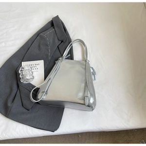 Detail of silver metallic tote bag with reflective surface and versatile long strap
