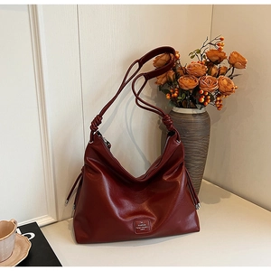 Detail of burgundy tote bag showing knotted strap design and matte leather finish