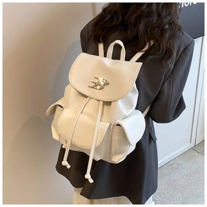 Detail view of white lychee texture backpack with silver B logo and multi-pocket design
