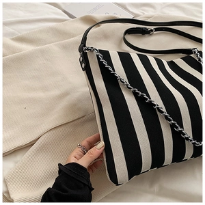 Close-up of striped canvas bag with leather strap and silver metal chain detail