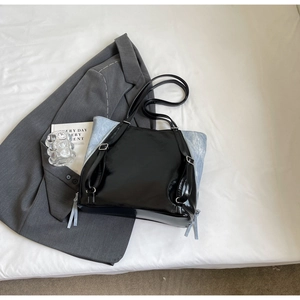 Detail of glossy black patent leather tote with light blue contrast and long tassels