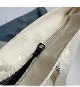 Detail view of the smooth black metal zipper and striped lining on the canvas tote bag