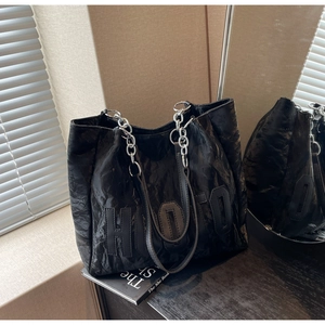 Detail of black pleated tote bag showing HOTO letter stitching and silver chain strap