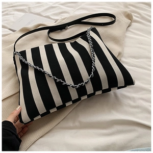Close-up of black and white vertical striped knit bag with silver chain and leather strap
