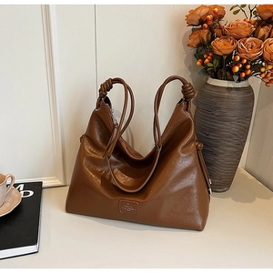 Detail of a brown bucket bag showing the knotted strap design and leather texture