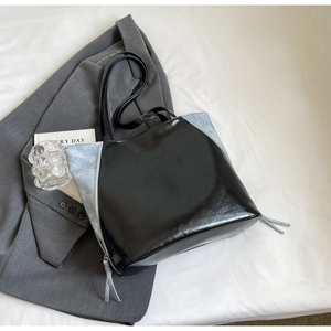 Detail of the high-shine black and blue patchwork tote bag with side fringe zipper