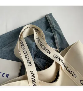 Detailed shot of heavy canvas tote with black branded webbing straps and sturdy handle