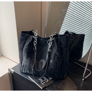 Detail of black tote bag featuring crinkled leather texture and silver chain strap