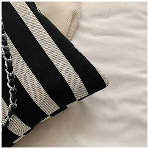 Detailed macro view of the black and white striped knit fabric and silver metal chain strap