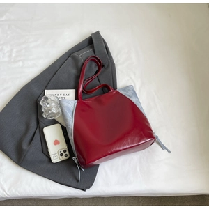 Detail of red and blue contrast tote bag styled with gray blazer on white background