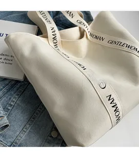 Detailed view of off-white canvas tote bag featuring black GENTLEWOMAN logo straps