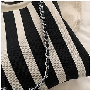 Detail of black and white striped knit bag with silver chain strap and woven texture