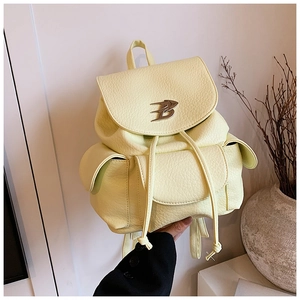 Detail of light yellow backpack showing lychee texture PU leather and metal B logo