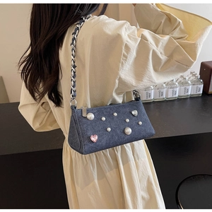 Détail du sac bandoulière en denim bleu avec perles, cœur en cristal rose et chaîne