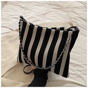 Macro detail of black and white striped canvas tote with silver chain and leather strap