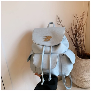 Detail of light blue pebble leather backpack featuring a metallic B logo and side pockets