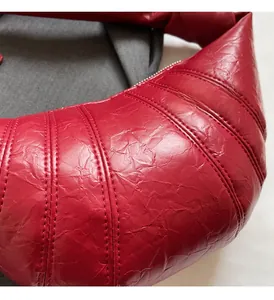 Macro shot of red croissant bag showing pleated texture and detailed stitching