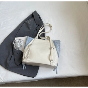 Detail of a large color-block tote bag in cream leather with blue suede sides and tassels