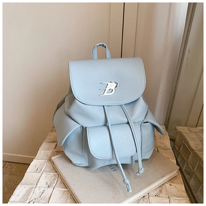 Detail of light blue lychee leather backpack with drawstring closure and silver B logo