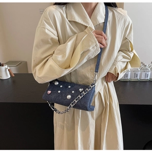 Détail d'un sac bandoulière en jean bleu avec perles blanches et cristal coeur rose