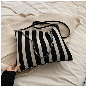 Detailed close-up of striped canvas tote bag with dual shoulder strap and metal chain