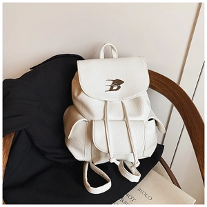 Detailed close-up of white lychee pattern leather backpack with metal B logo on wood seat