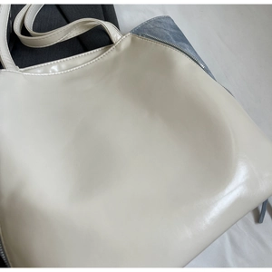 Detail shot of the minimalist creamy-white PU leather tote bag with secure zipper closure