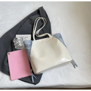 Detail view of contrast color tote bag with smooth white PU leather and blue denim texture