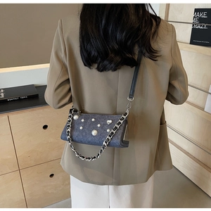 Détail du sac bandoulière en denim bleu avec perles blanches et bandoulière chaîne