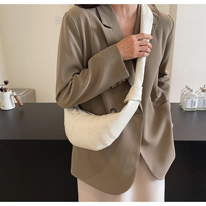 Detail of cream croissant bag featuring textured leather and a knotted shoulder strap