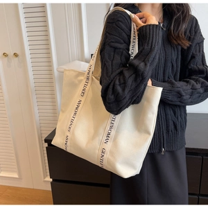 Close-up of durable canvas tote bag featuring branded Gentlewoman straps and minimalist texture