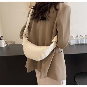 Detail of off-white croissant bag with pleated leather texture and knotted shoulder strap