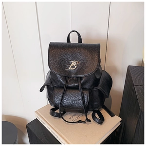 Detail of lychee pattern leather backpack with silver bird logo and drawstring closure