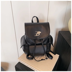 Close-up of black pebble leather backpack featuring silver B-logo and drawstring closure