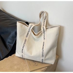 Detailed macro view of the cream canvas tote bag with black GENTLEWOMAN branded strap