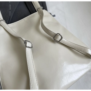 Close-up of adjustable straps and silver metal buckles on a beige faux leather tote bag