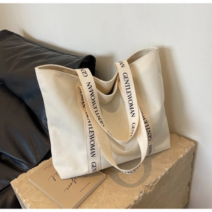 Detail of canvas tote shoulder strap with black Gentlewoman logo text on stone base